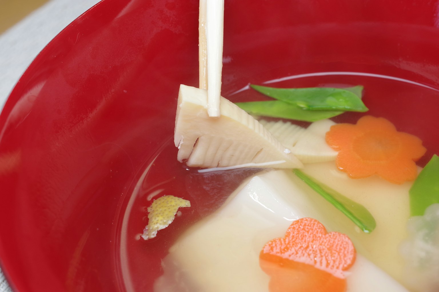 Sopa de miso en un tazón rojo con verduras coloridas y brotes de bambú