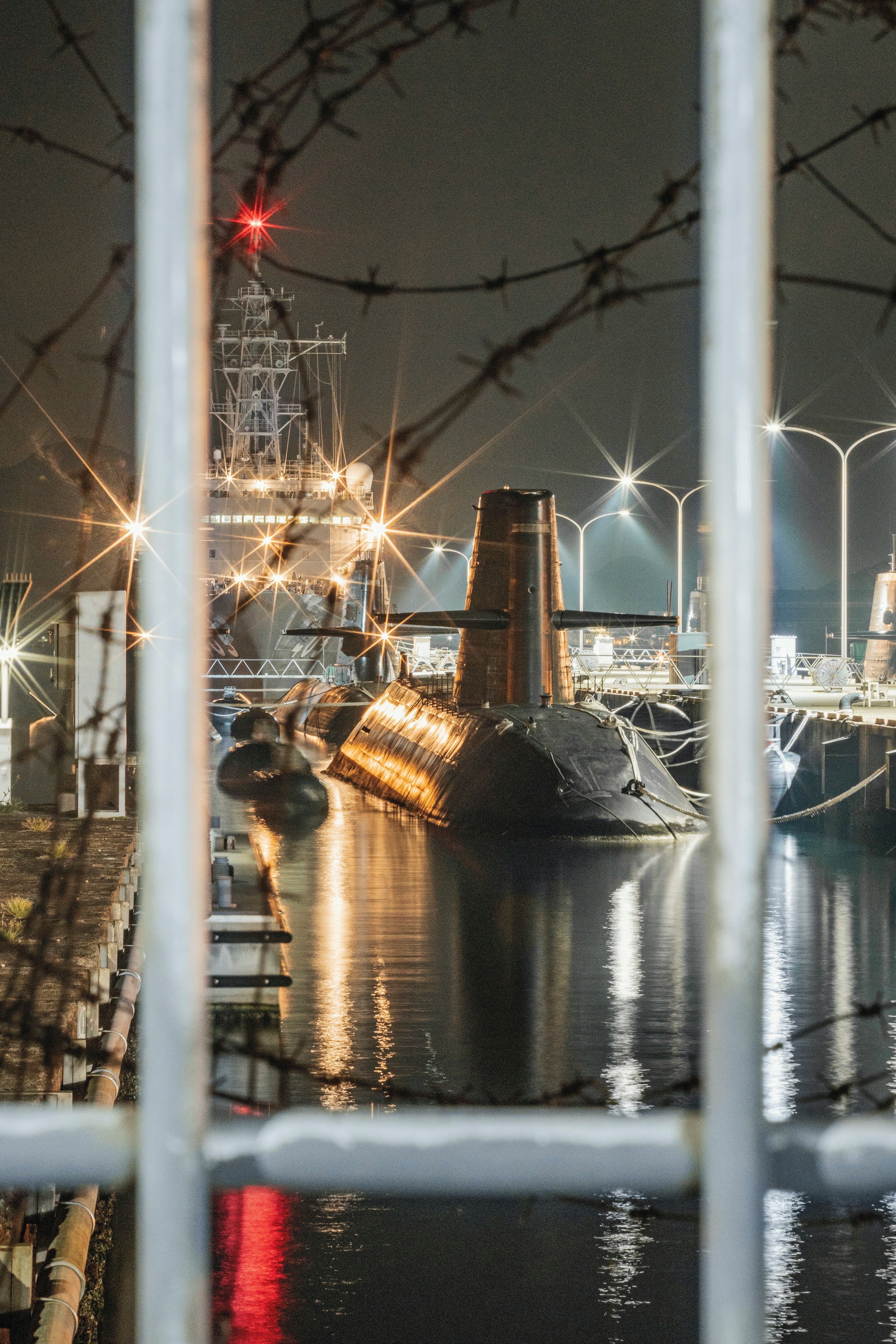 港湾の係留施設に並ぶ潜水艦と夜の水面
