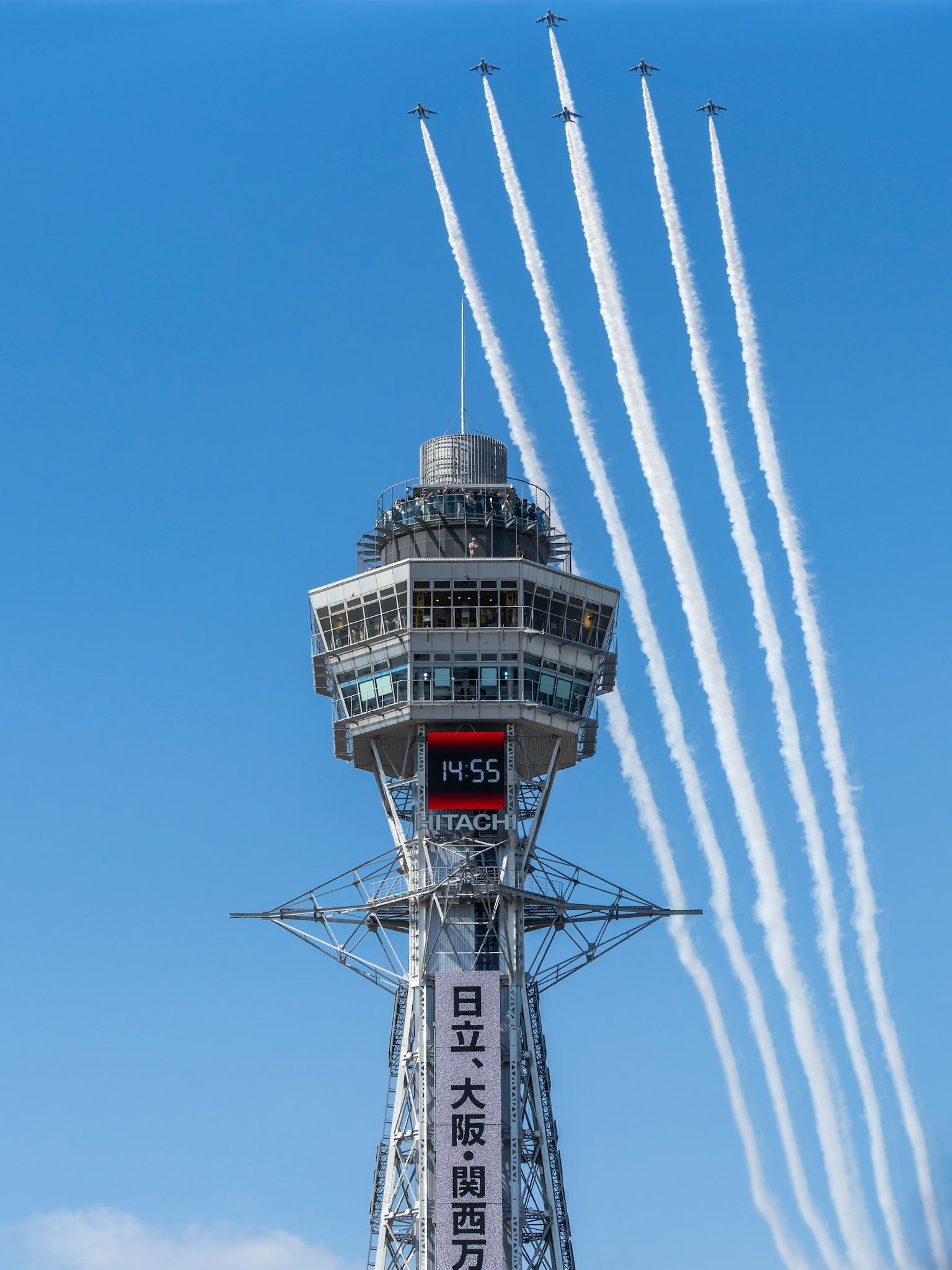 Tsutenkaku Tower in Osaka with aircraft smoke trails in the blue sky
