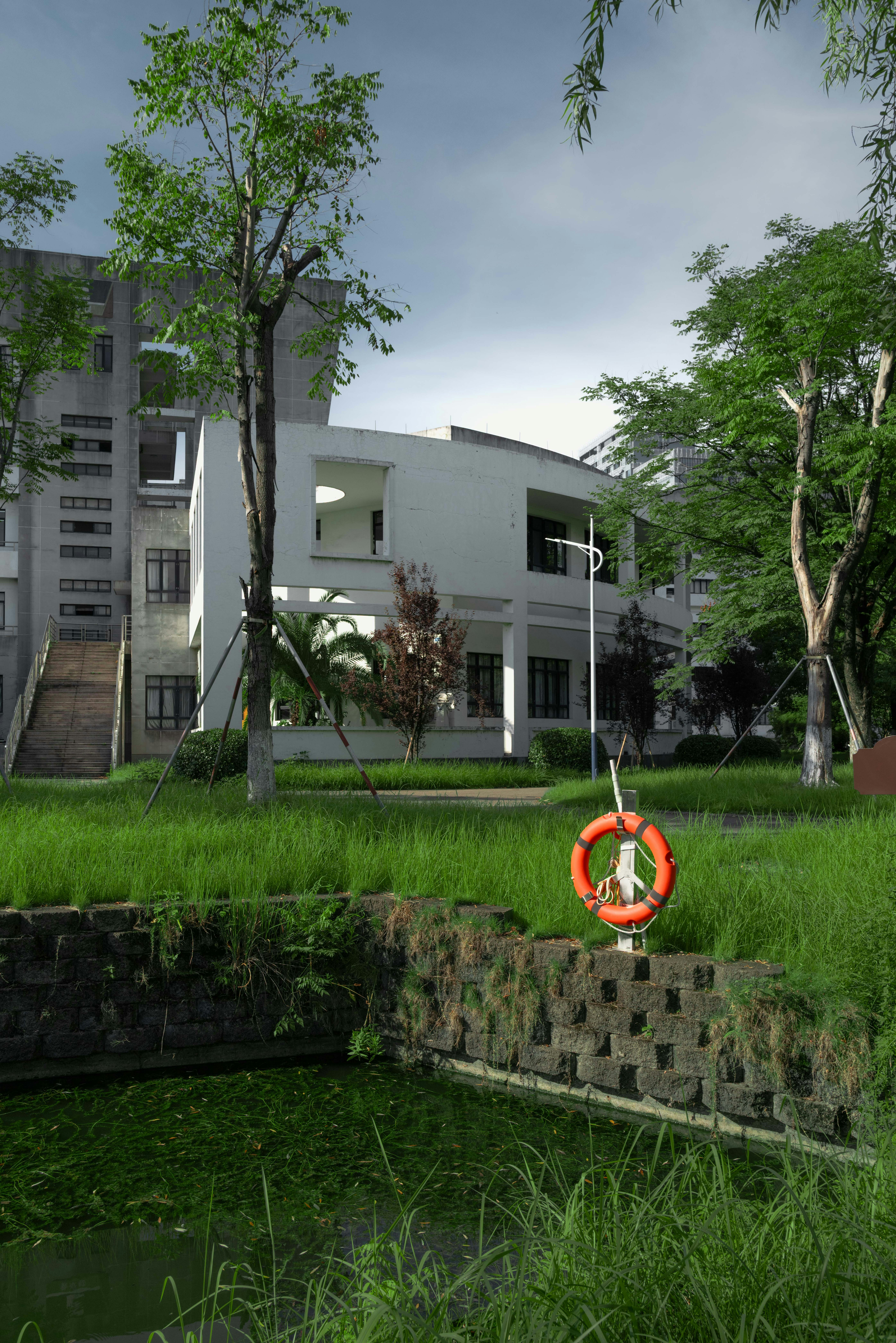 orange life buoy hanging in a garden courtyard with a white building