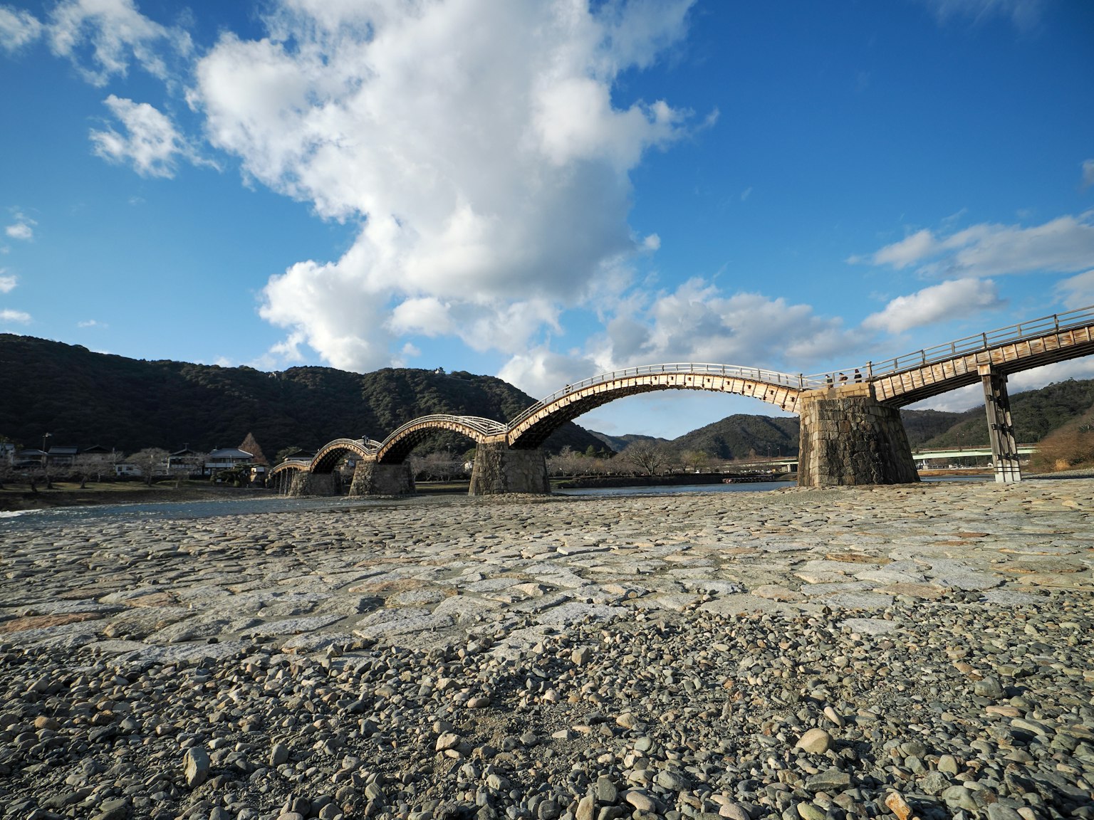 Beau pont en arc traversant une rivière avec un ciel bleu et des nuages blancs