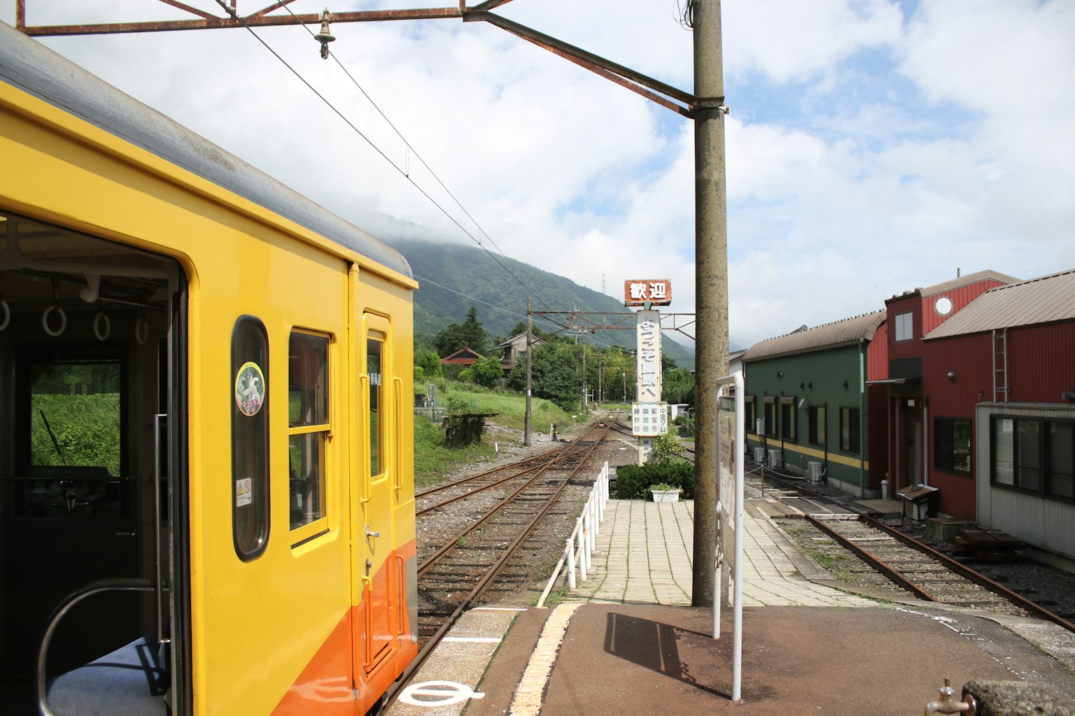 Train coloré à une gare pittoresque avec des montagnes en arrière-plan
