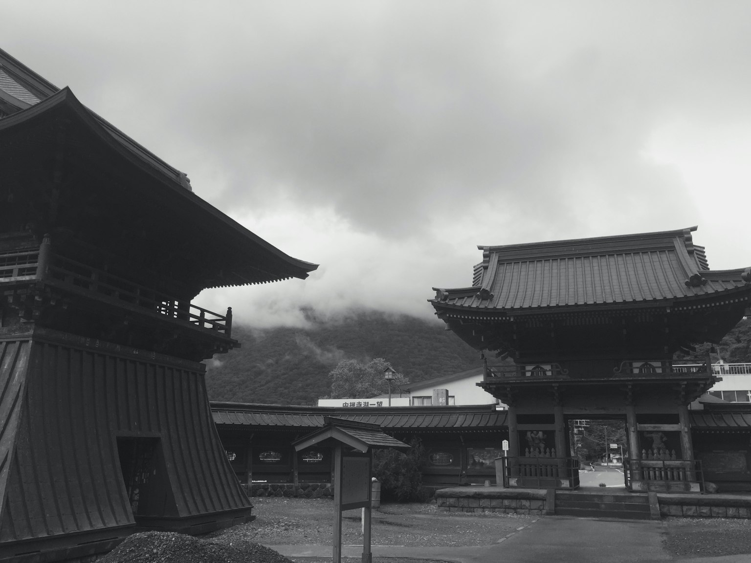 Vista escénica de edificios tradicionales japoneses con montañas al fondo y cielo nublado