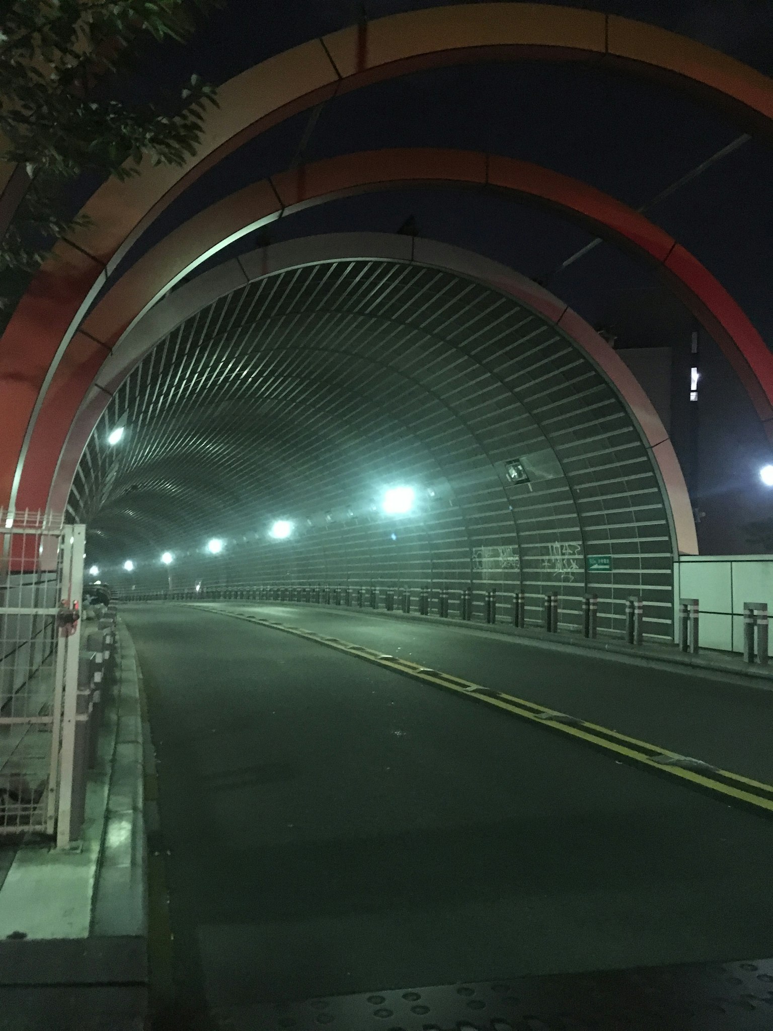 สะพานโค้งสีสันสดใสที่มีแสงสว่างในตอนกลางคืนและถนนว่างเปล่า
