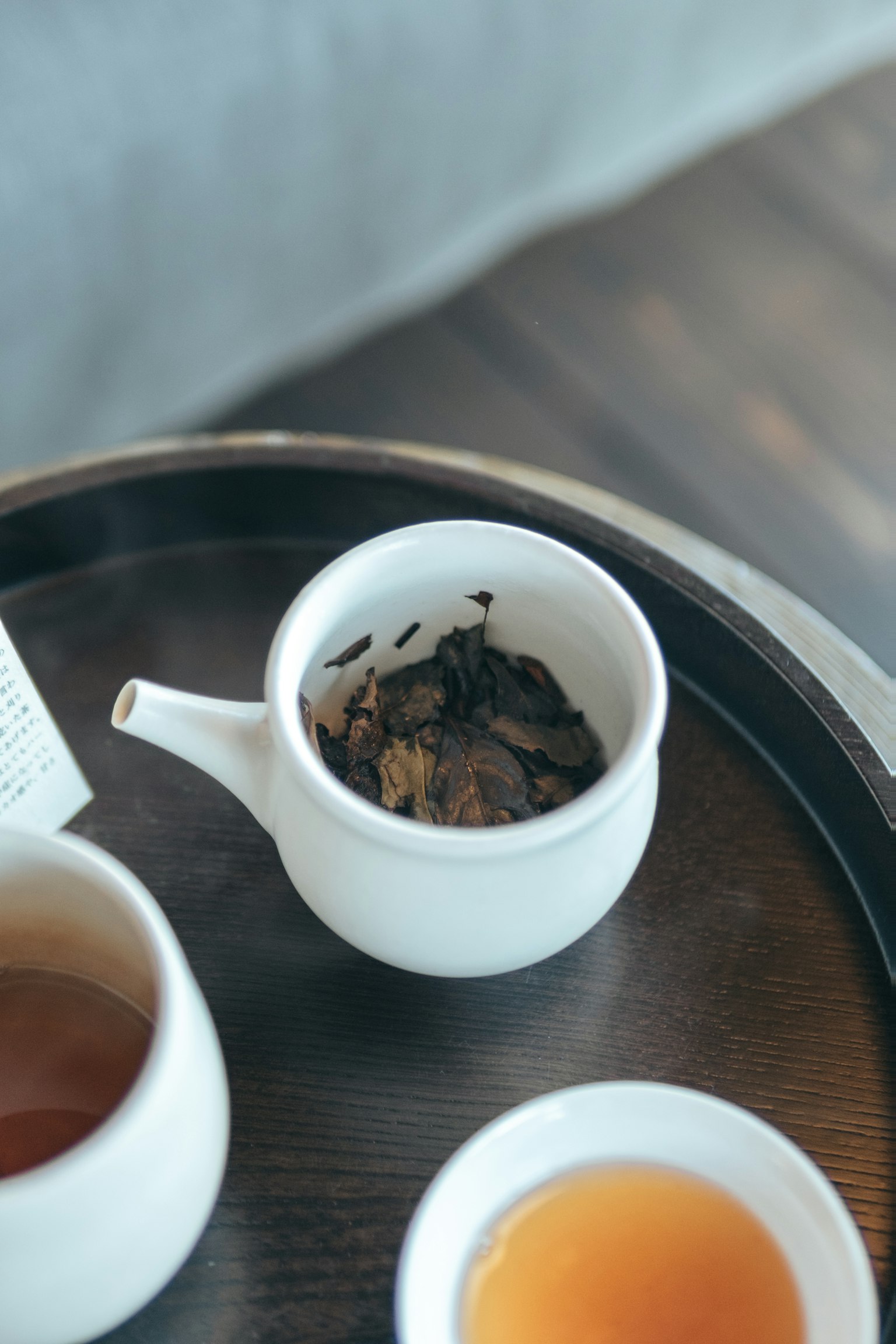白色茶壶与茶叶和杯子放在木托盘上