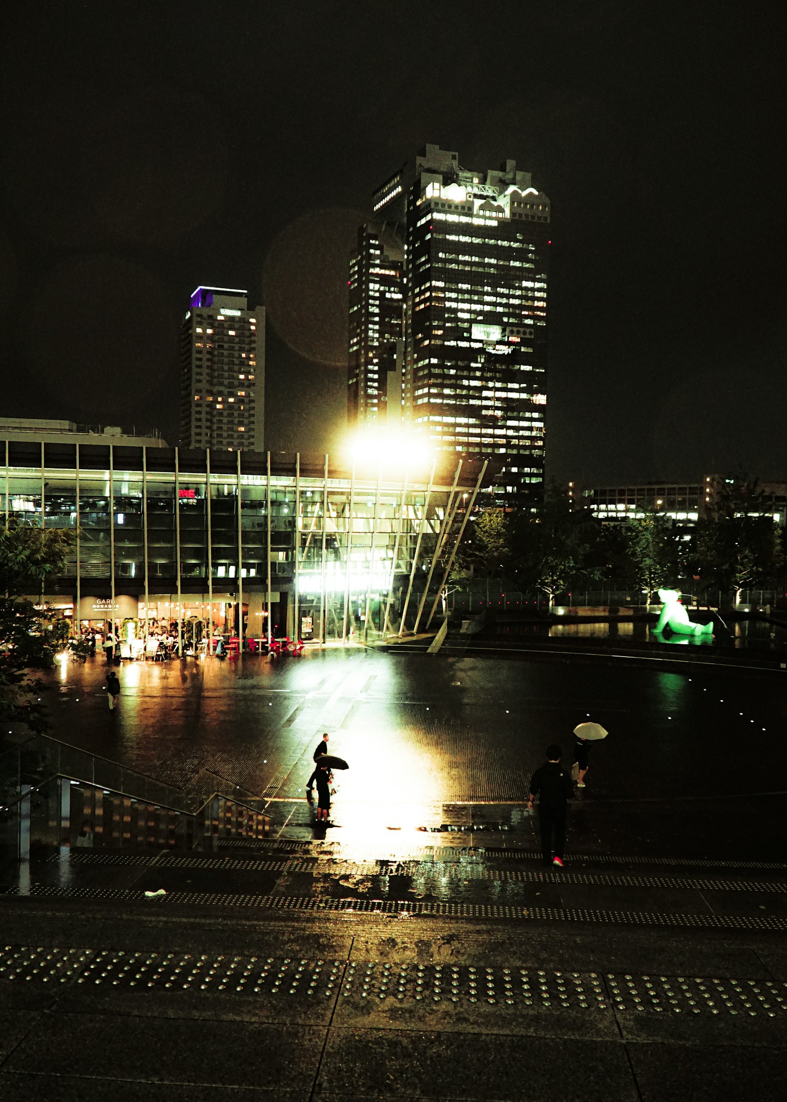 Night cityscape featuring skyscrapers and reflections on water bright lights