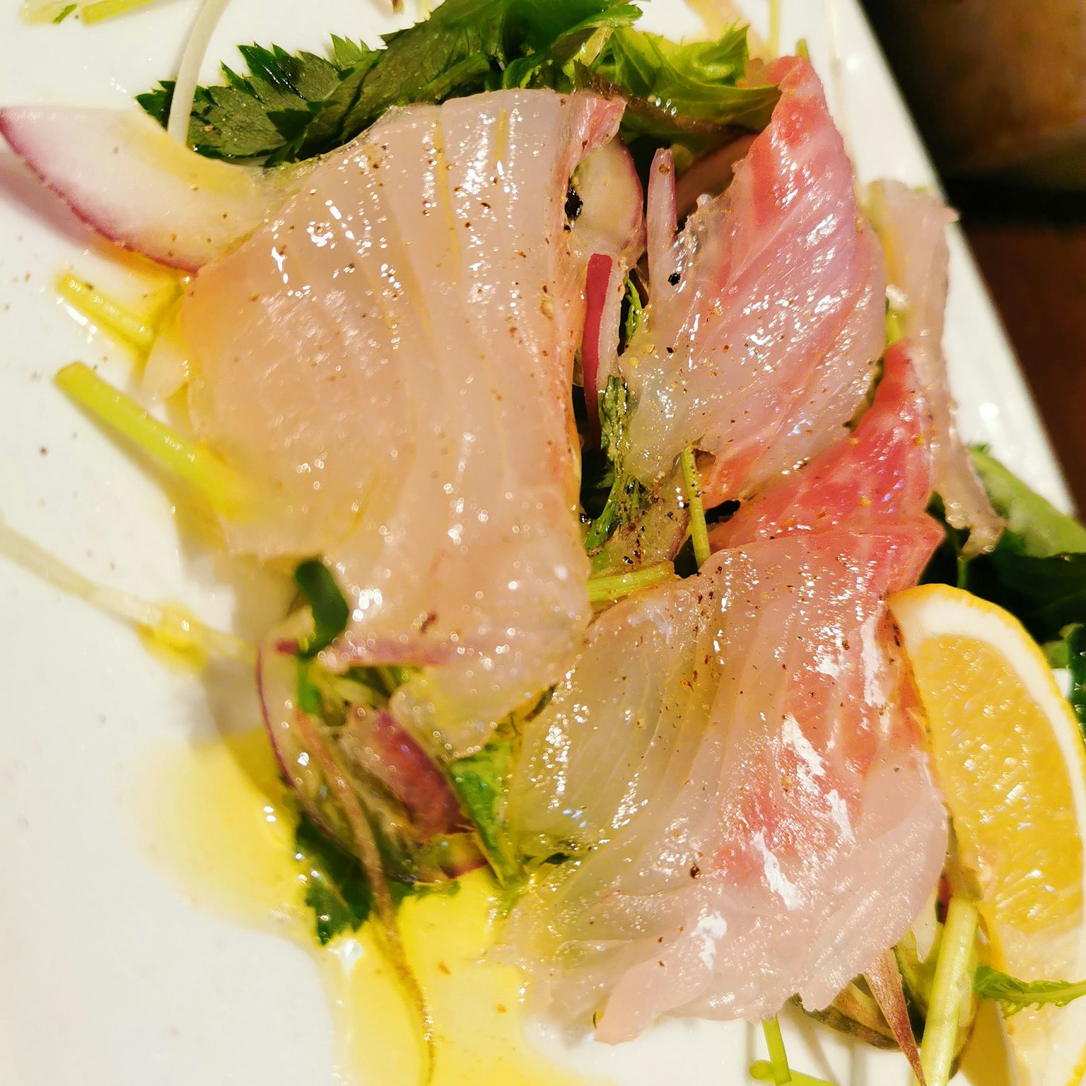 Plato de sashimi fresco con guarnición de hierbas y limón