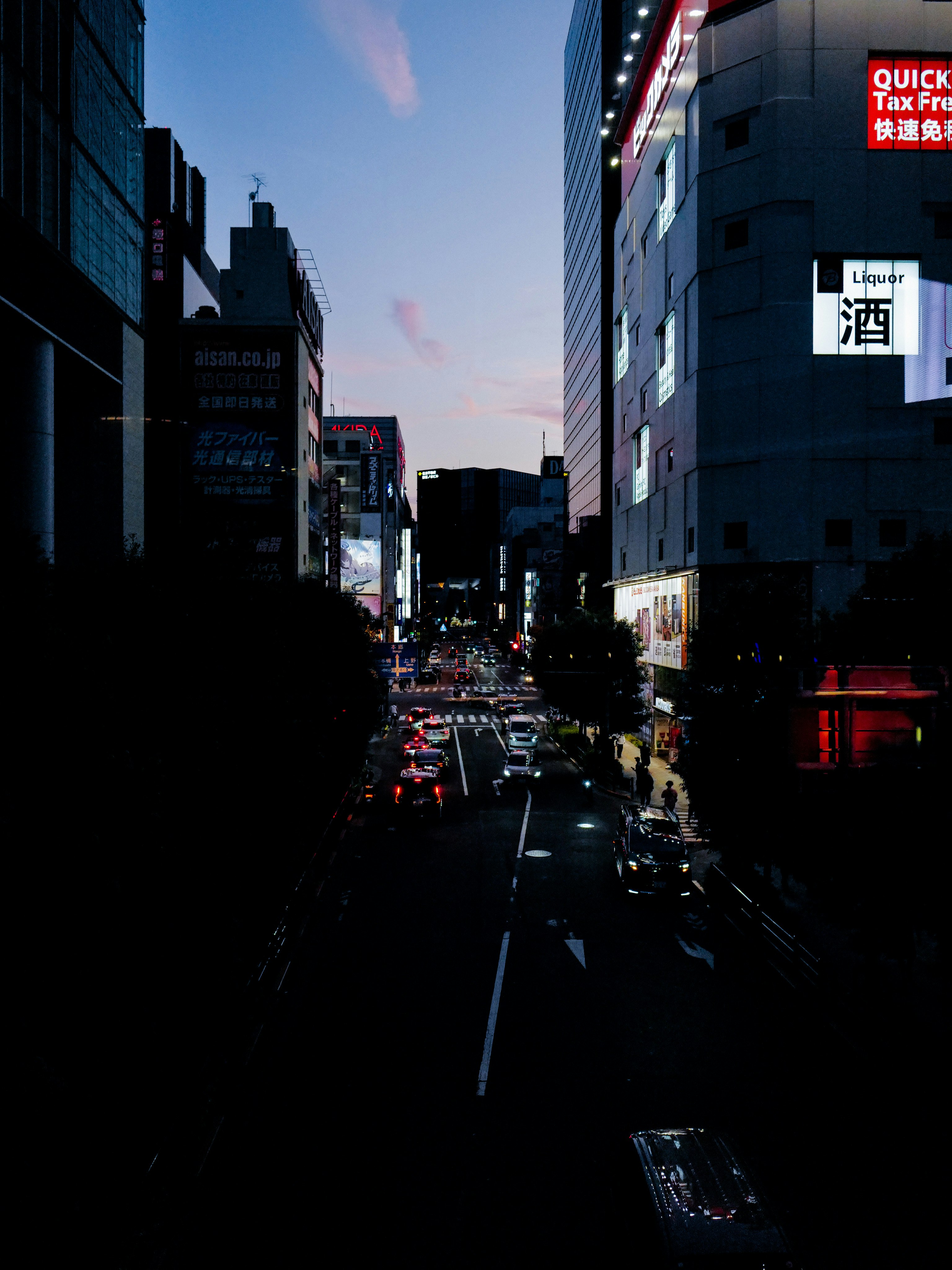夕暮れの路地に並ぶ看板とネオンの街並み