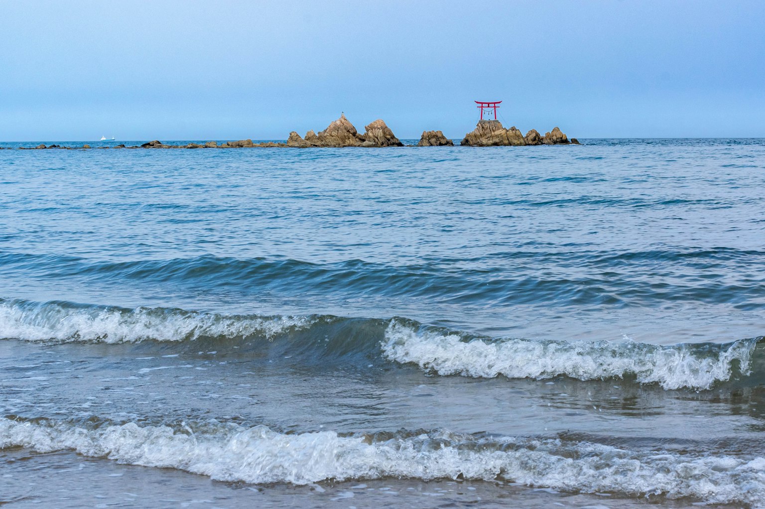 Vista escénica de un mar tranquilo con una isla rocosa a lo lejos