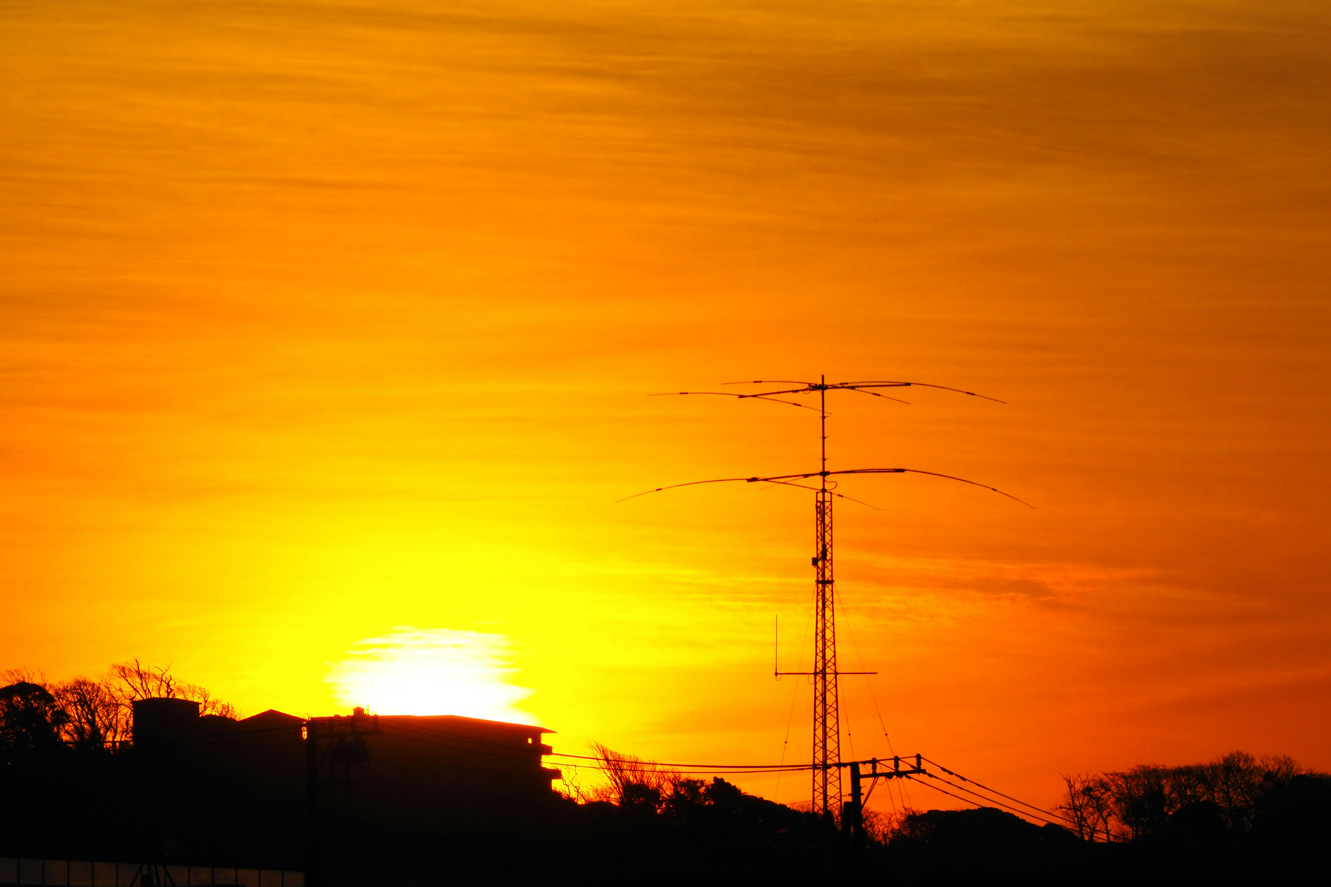 sagoma di linee elettriche e traliccio contro un cielo al tramonto