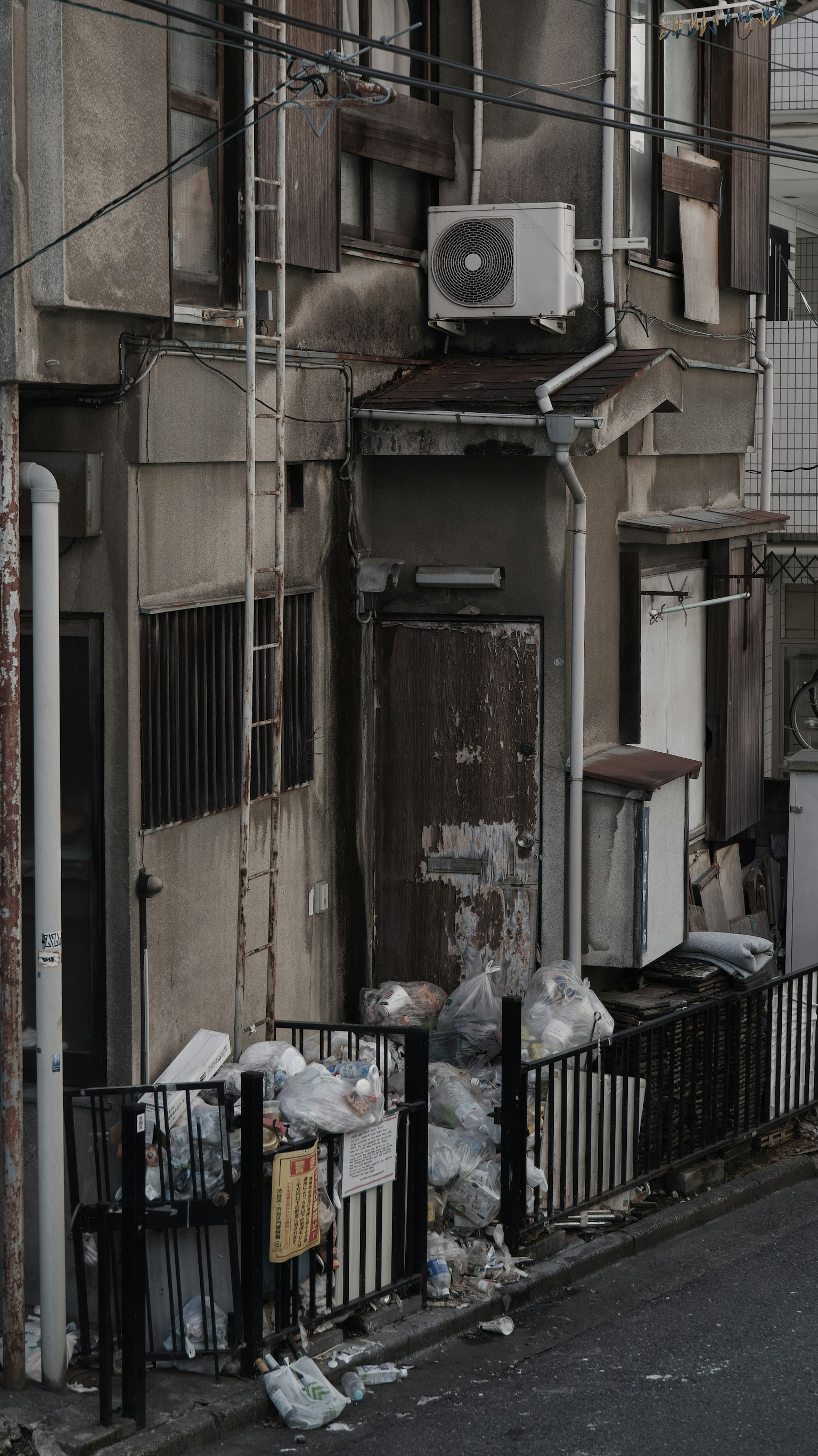 Exterior of an old building with scattered trash bags