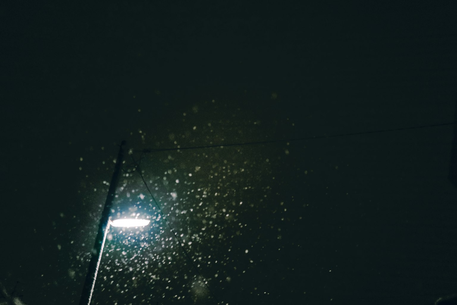 街灯照亮雨滴与黑暗的天空