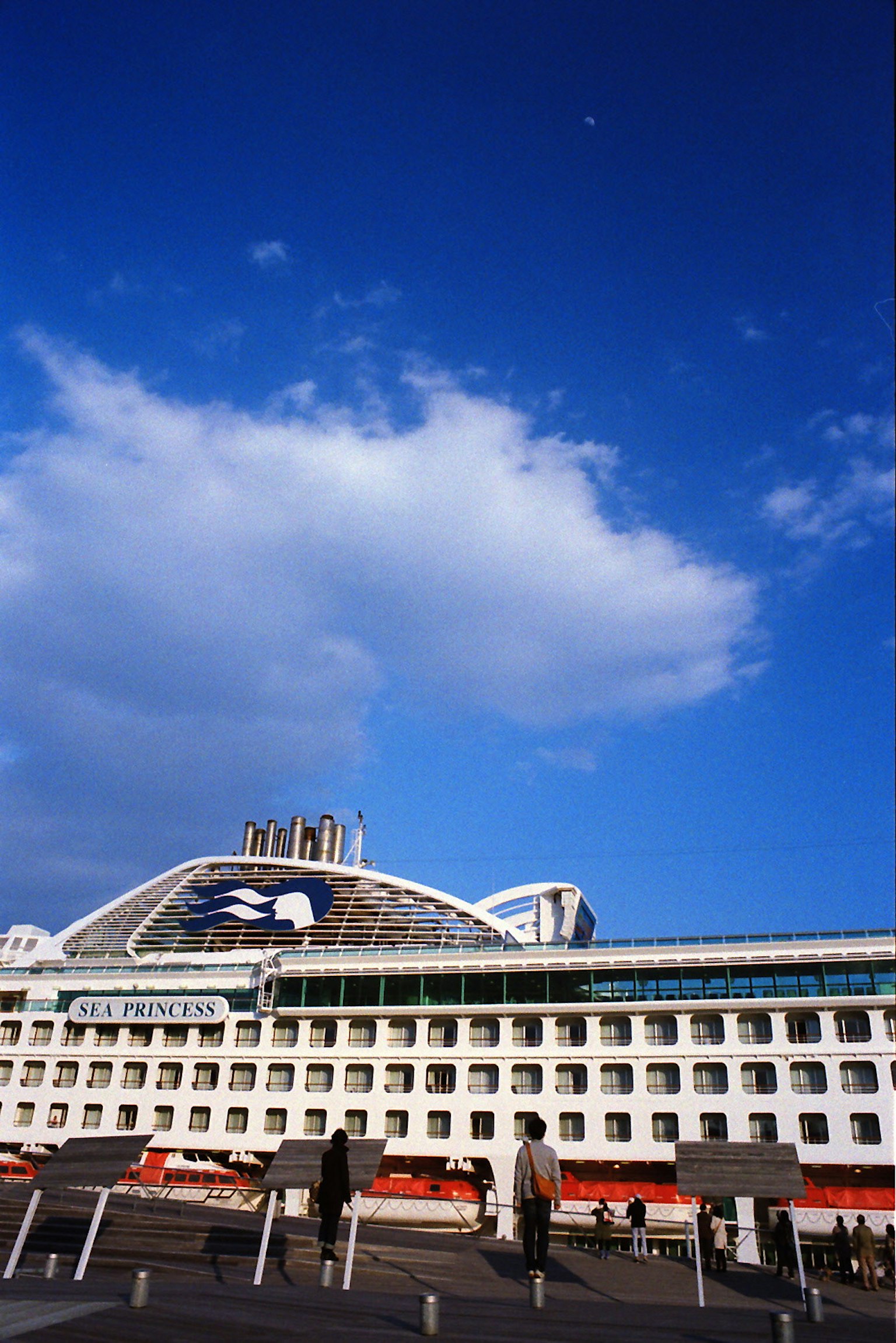Moderne Gebäudeaußenansicht unter blauem Himmel mit Wolken und Menschen