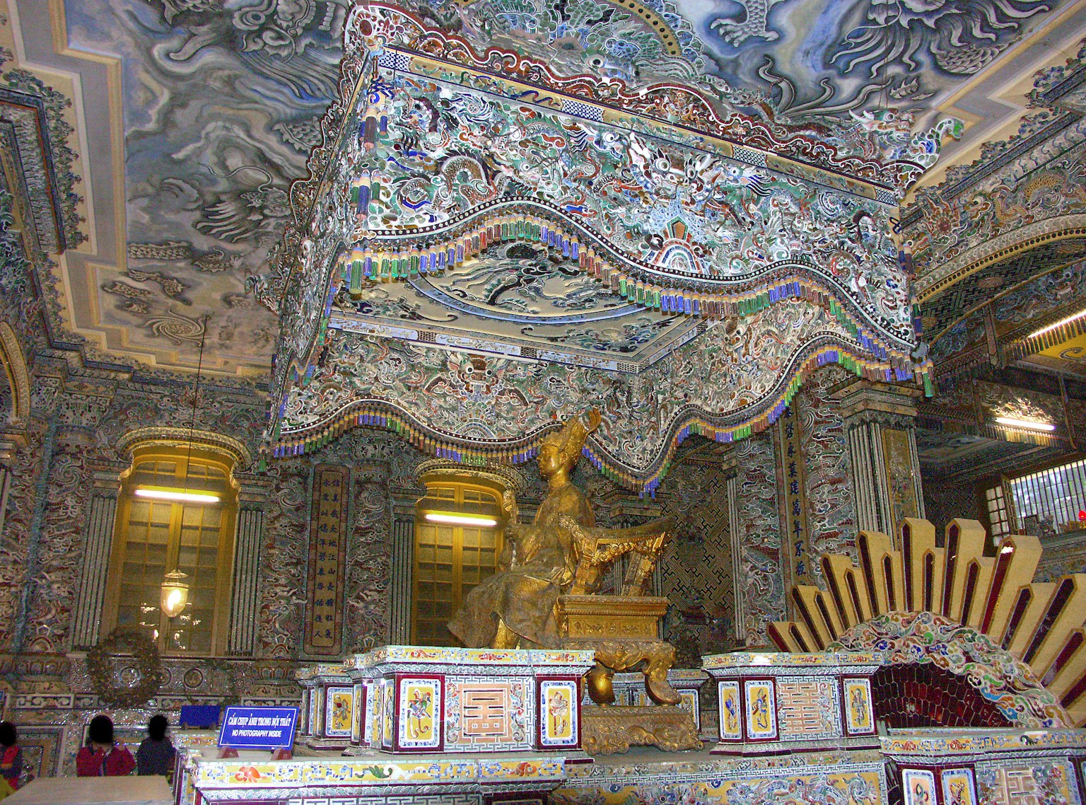 Innenraum eines aufwendig dekorierten Zimmers mit komplizierten Mustern an Wänden und Decke mit einer auffälligen goldenen Skulptur