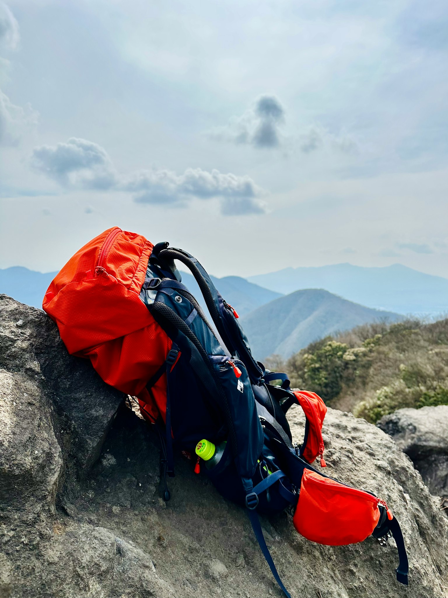 Roter Rucksack auf einem Felsen mit Bergen im Hintergrund