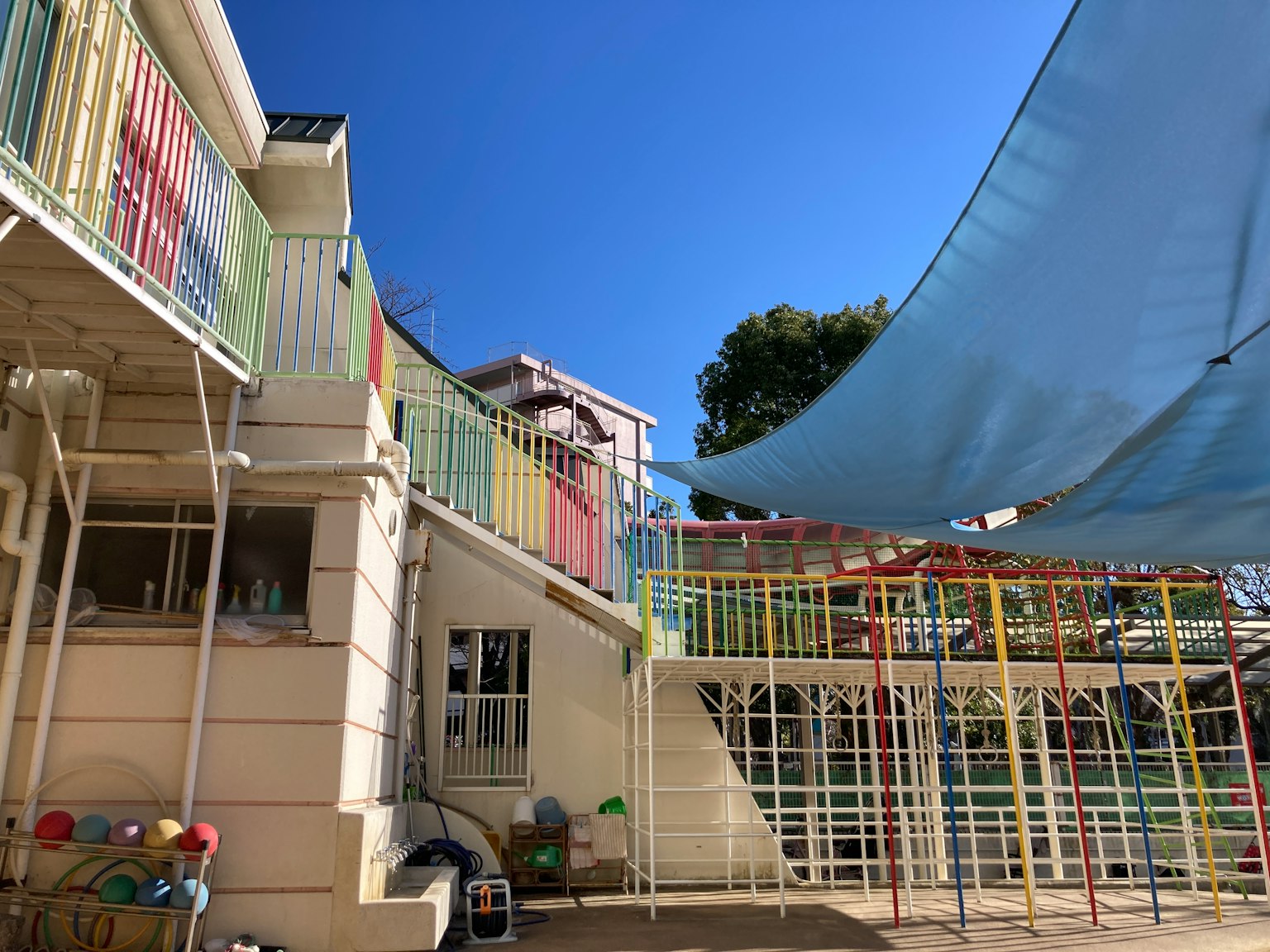 Aire de jeux d'une école maternelle avec des structures colorées et un ombrage bleu