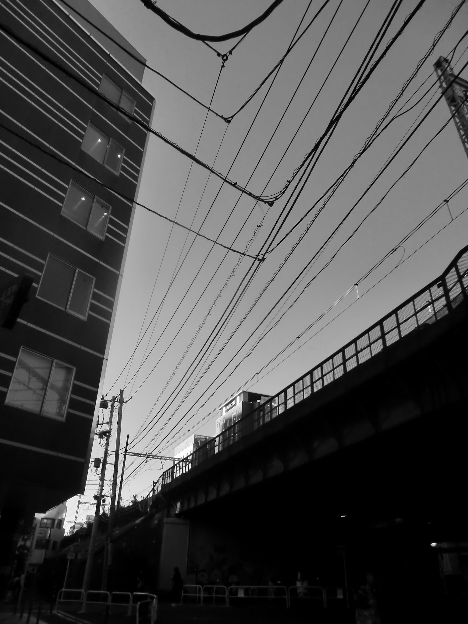 Cảnh quan đô thị đen trắng với hình bóng của tòa nhà và đường ray trên cao