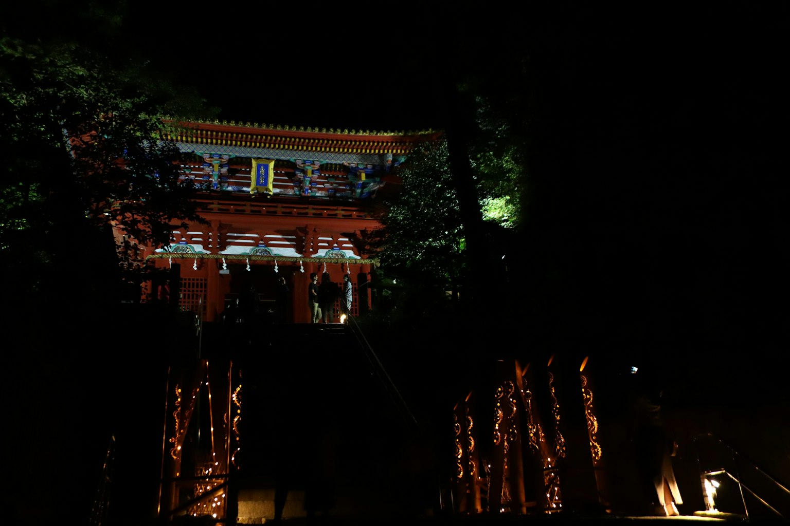 Hermoso edificio del santuario iluminado por la noche rodeado de árboles verdes