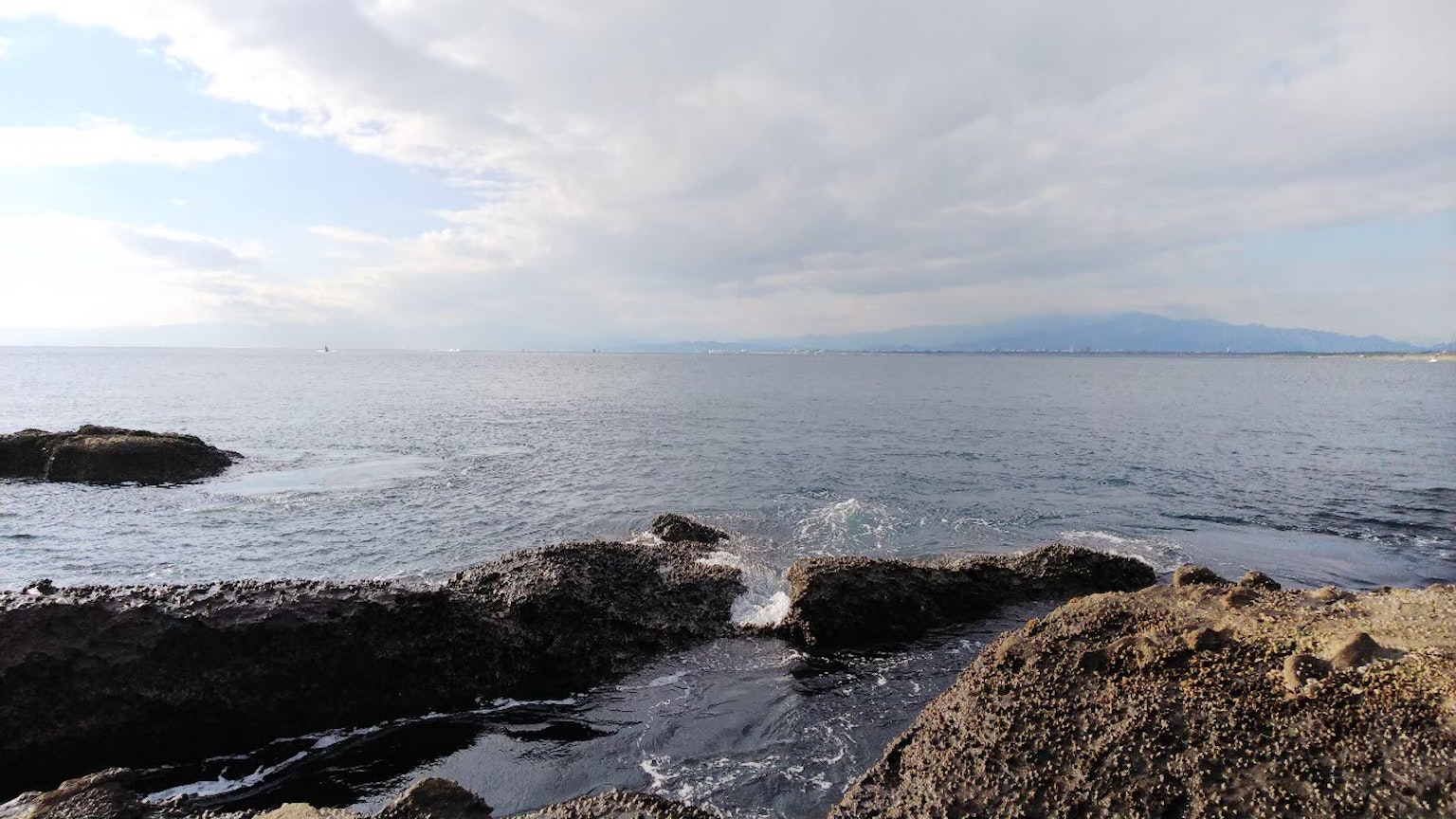 Seascape with rocky shoreline calm water and cloudy sky