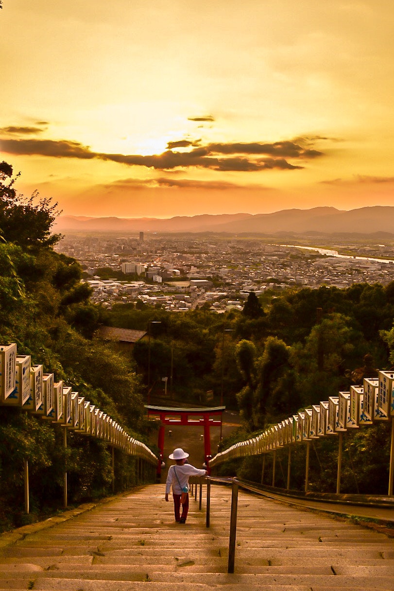 夕焼けの下、坂道の鳥居と街並みを見下ろす眺望