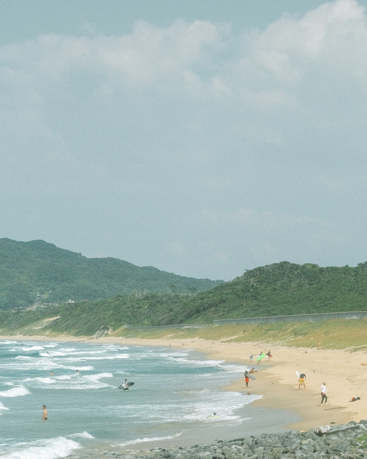 Vista panoramica della spiaggia con persone che si godono la riva e onde leggere