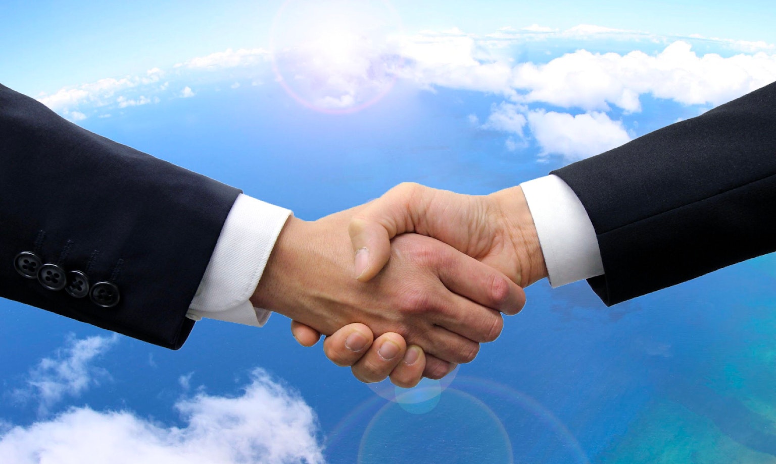 Hombres de negocios dándose la mano bajo un cielo azul