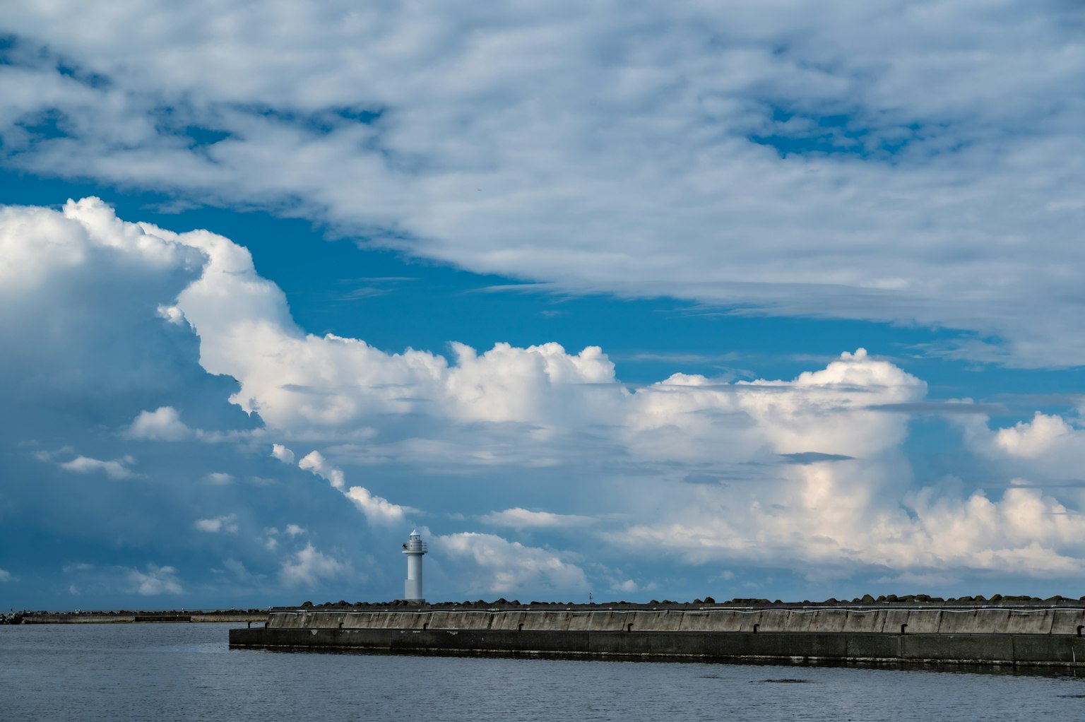 Paesaggio marittimo con un faro sotto un cielo blu e nuvoloso