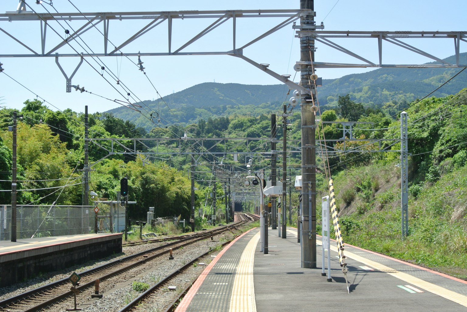 Plateforme de train tranquille entourée de montagnes vertes