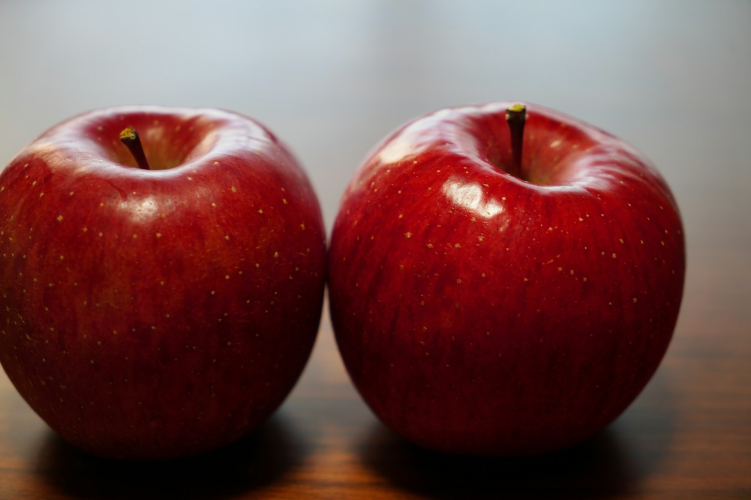 Two red apples on a wooden table