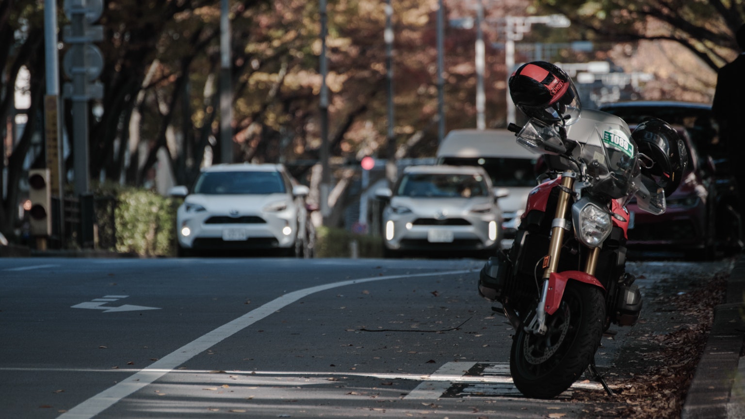 Motocicleta roja estacionada junto a coches en una calle de la ciudad