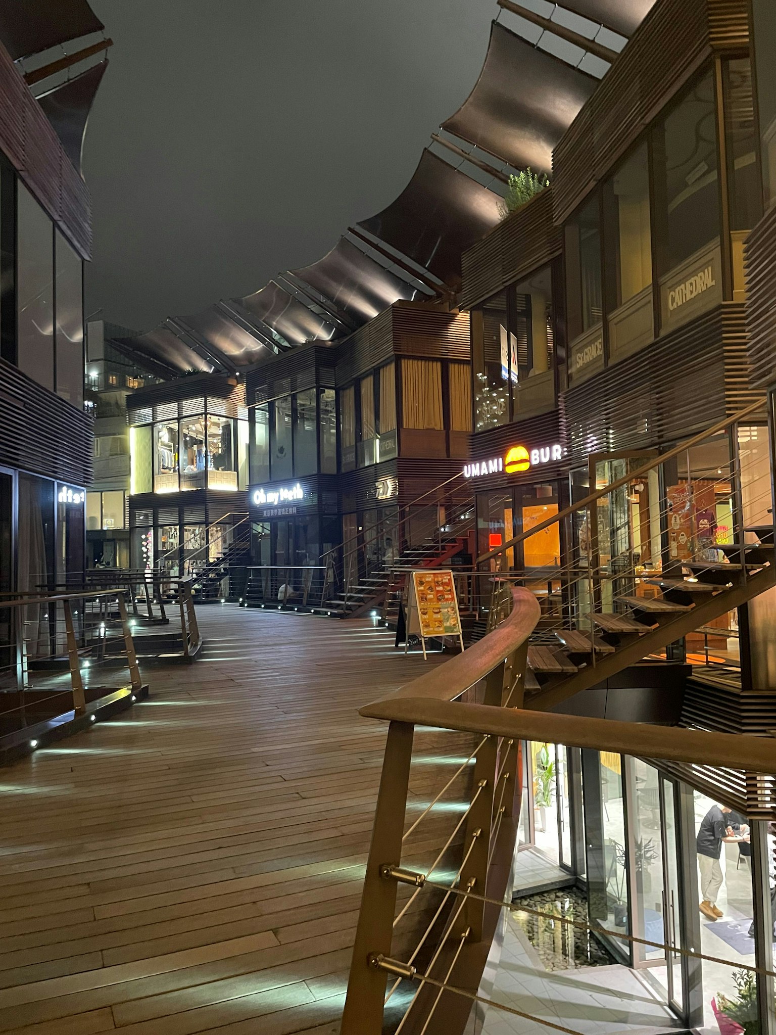 Tampilan interior ruang komersial modern dengan desain kayu dan kaca di malam hari
