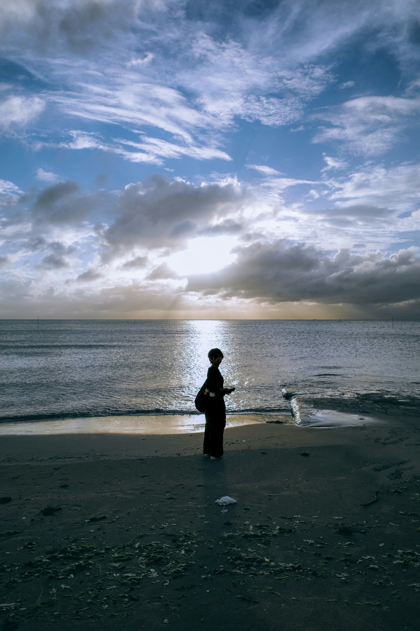 silhouette seseorang berdiri di pantai saat matahari terbenam