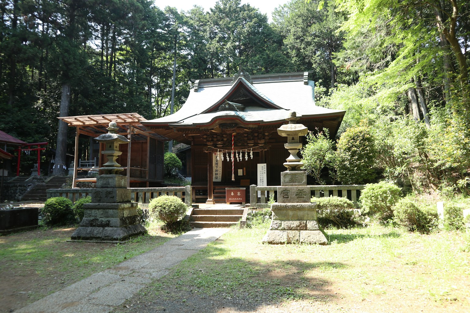 Traditional shrine building surrounded by greenery with stone lanterns