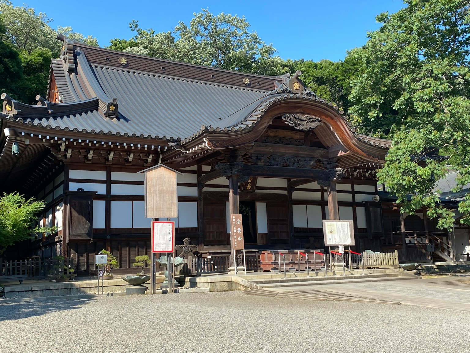 传统日本寺庙外观，屋顶上有精美的雕刻，周围绿树成荫