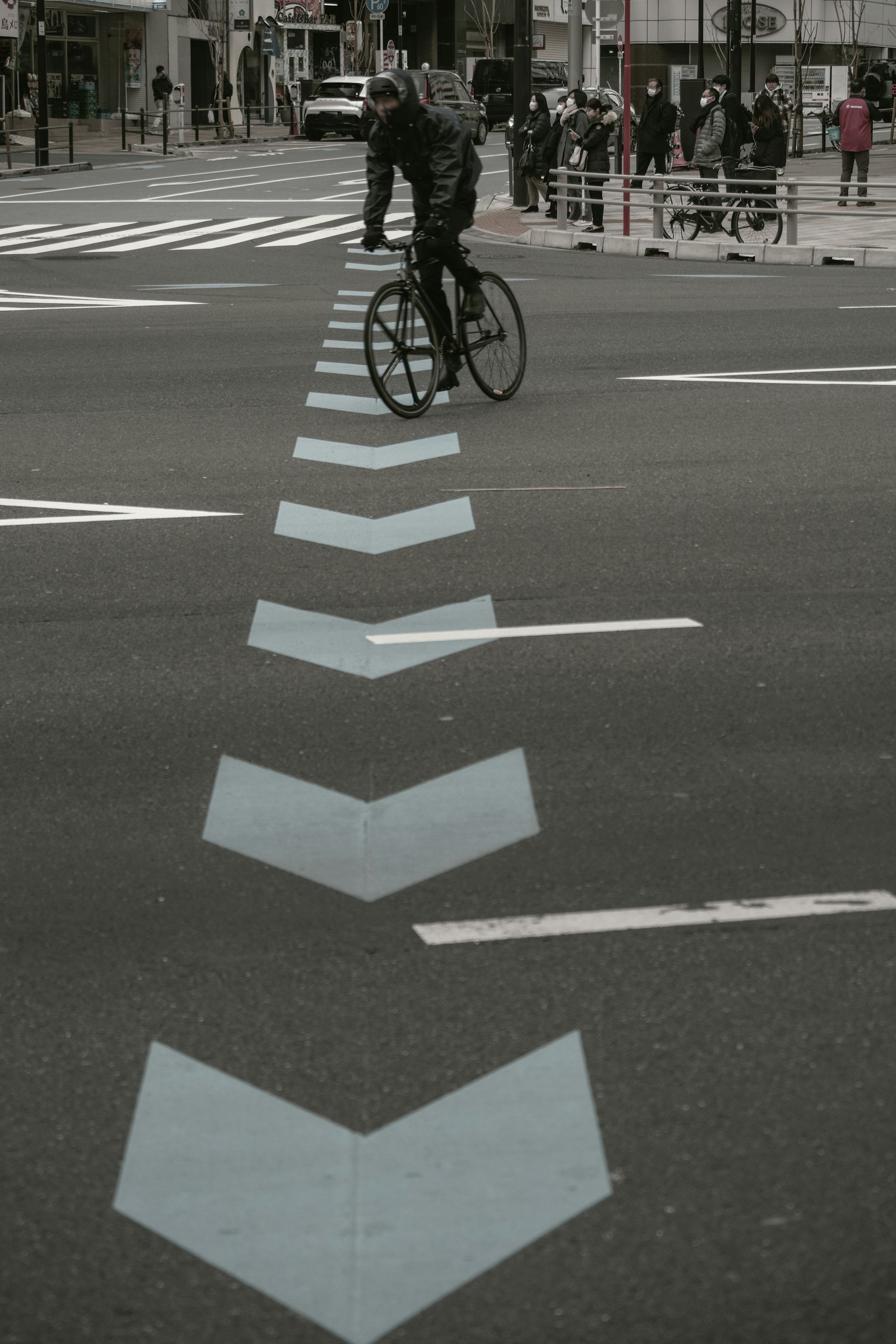 Un ciclista pasando sobre marcas de flecha azul en un entorno urbano