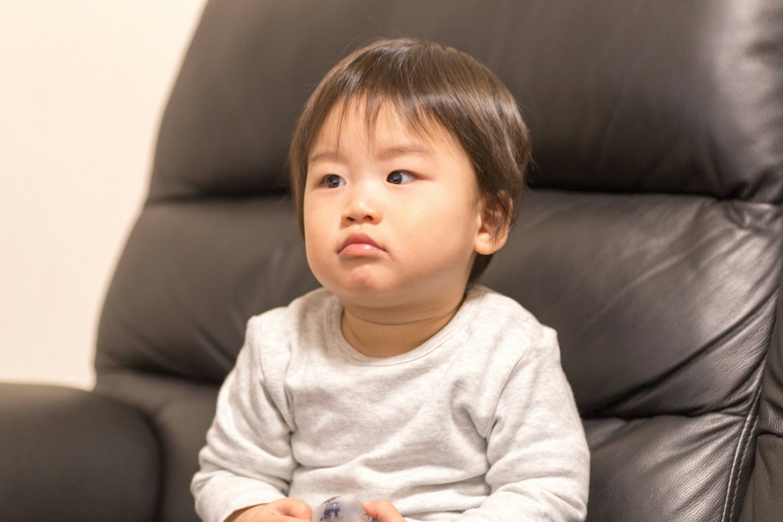 小孩坐在黑色沙发上沉思