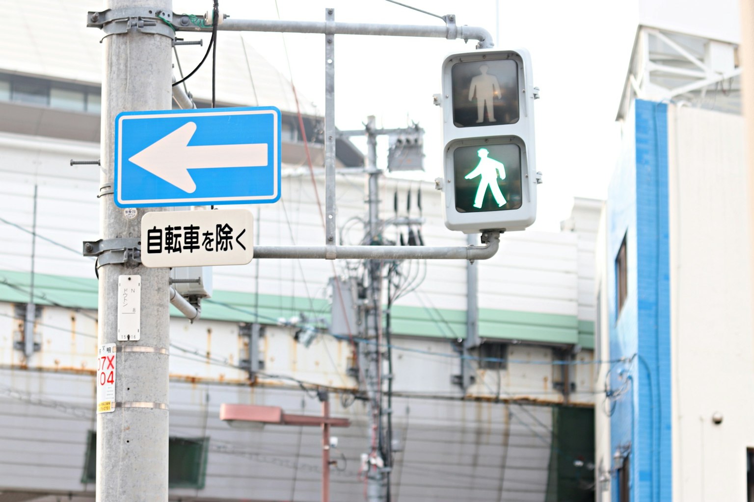 Kreuzungsszene mit grünem Fußgängersignal und linksabbiegendem Schild
