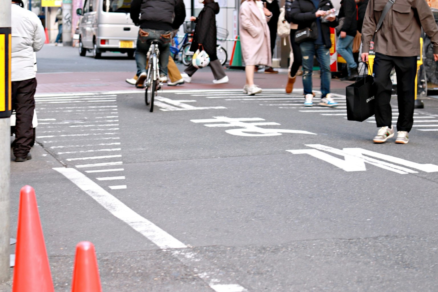 สี่แยกถนนที่พลุกพล่านมีคนเดินจักรยานและกรวยสีแดง