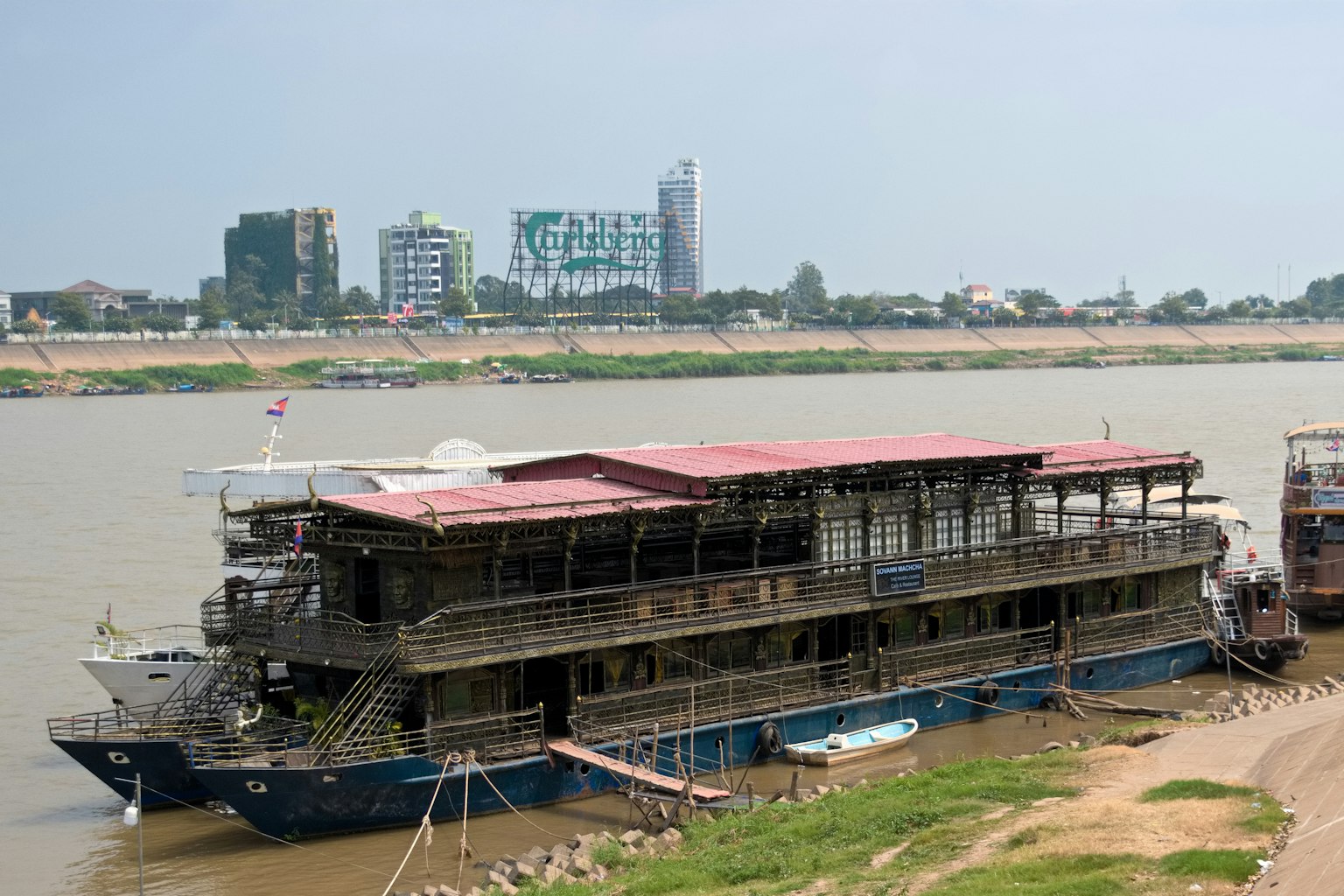 Un barco atracado junto al río con un horizonte urbano al fondo