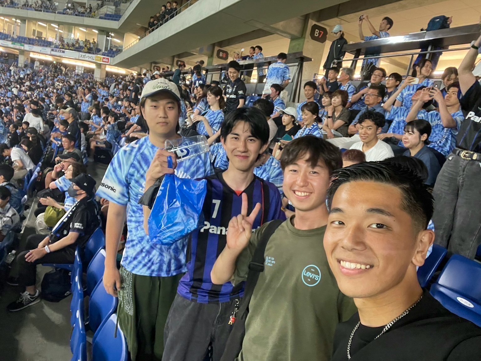 Selfie of young fans at a soccer match with a crowd in the background