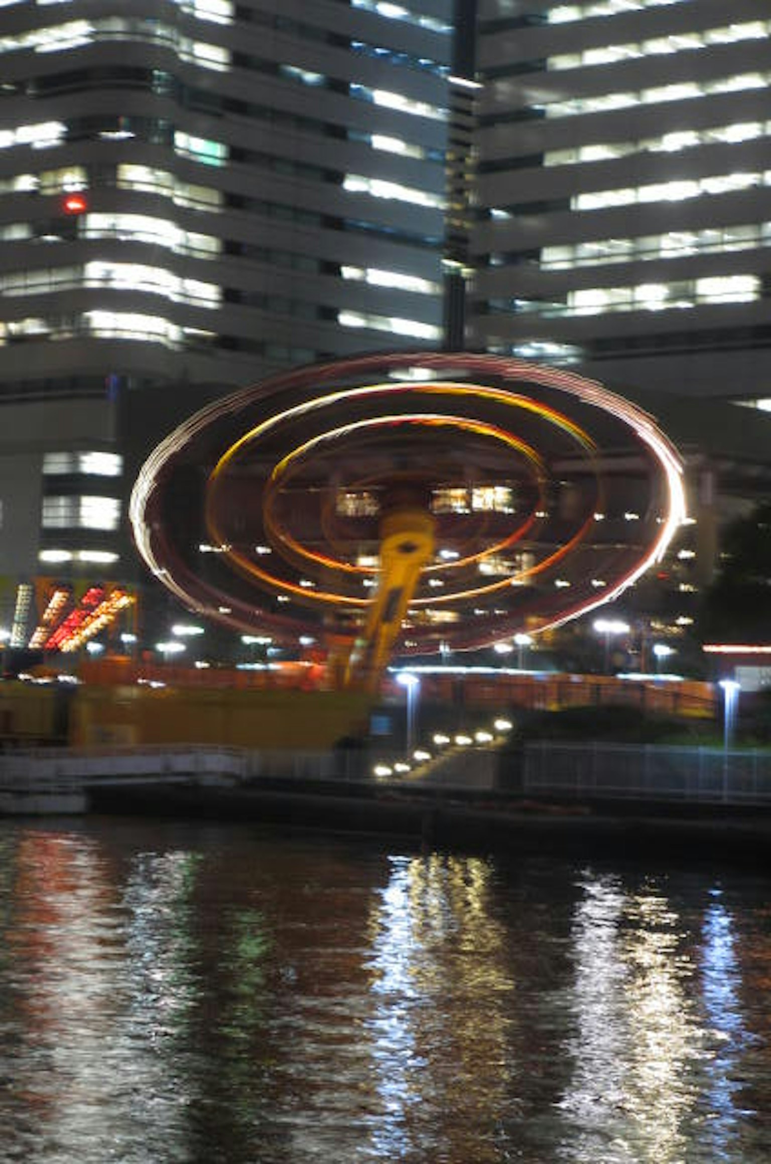 夜间照亮的旋转游乐设施与摩天大楼的背景