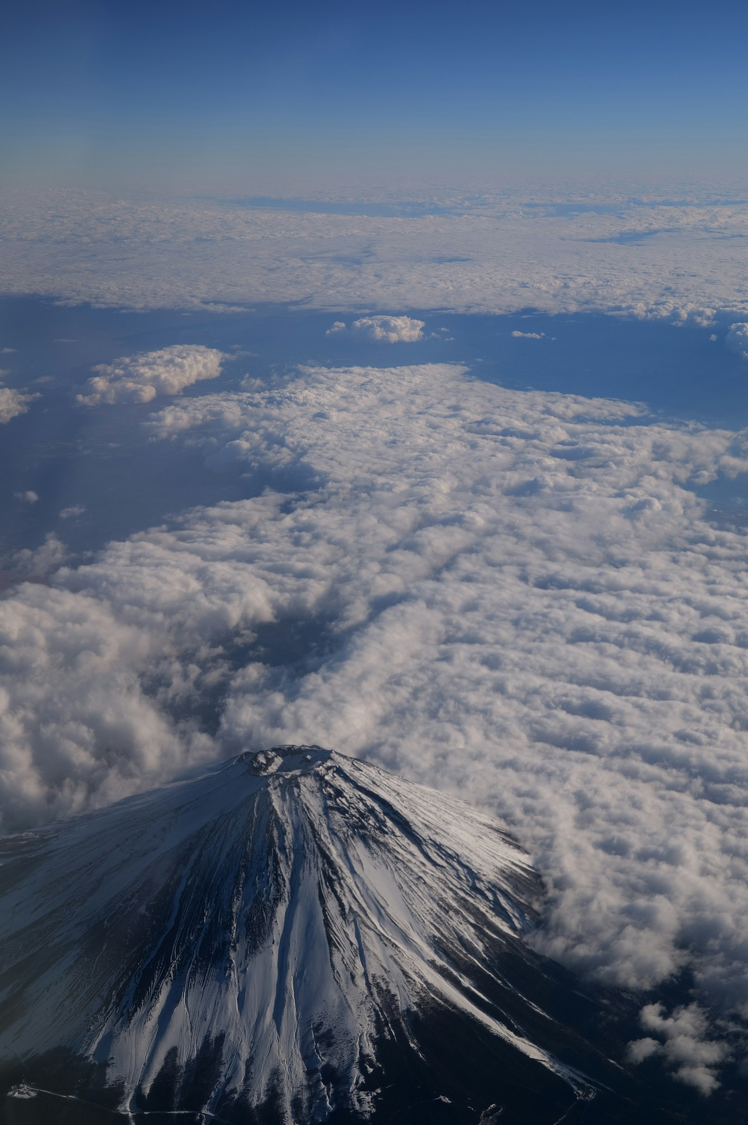 Cima nevada del Monte Fuji que se eleva sobre un mar de nubes en un cielo azul claro