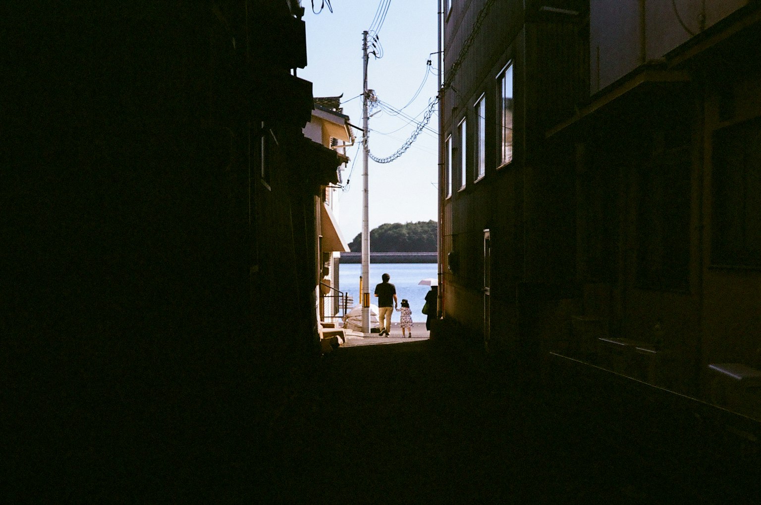 Silhouettes de personnes regardant la mer depuis une ruelle étroite