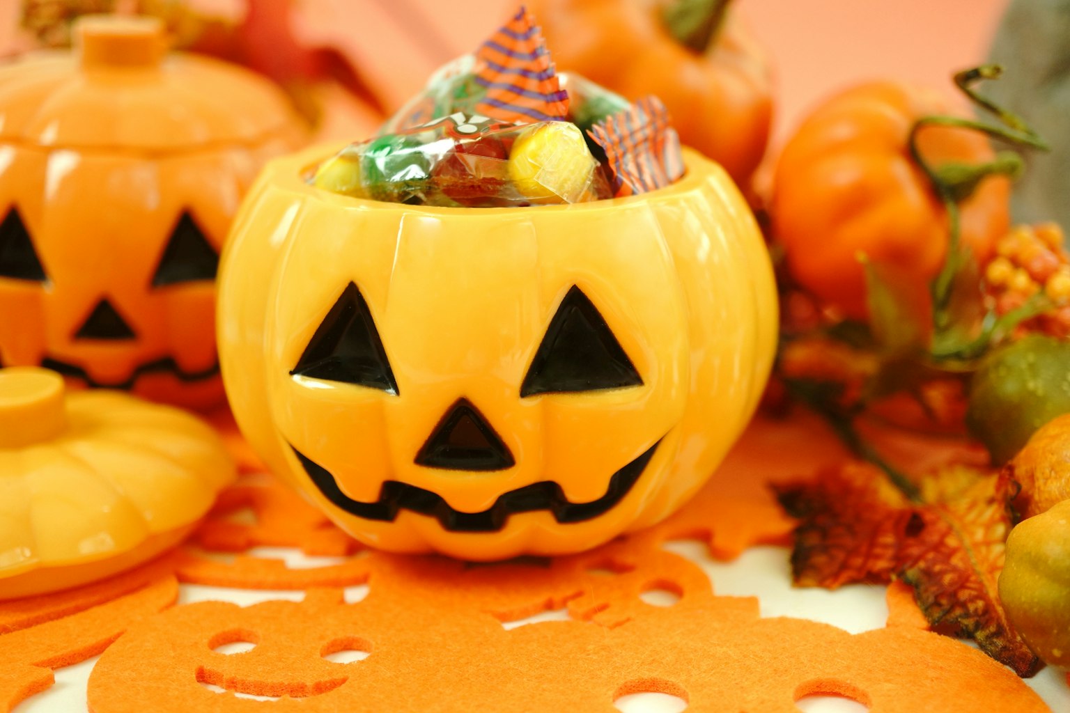 Contenedor de calabaza naranja lleno de dulces y decoraciones de otoño