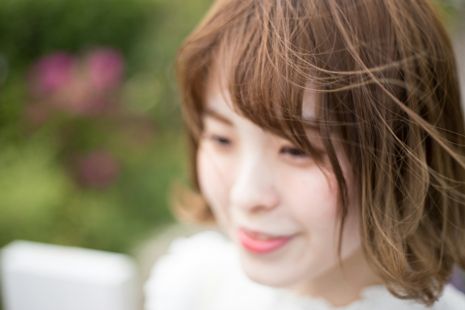 年轻女性在户外微笑，背景柔和