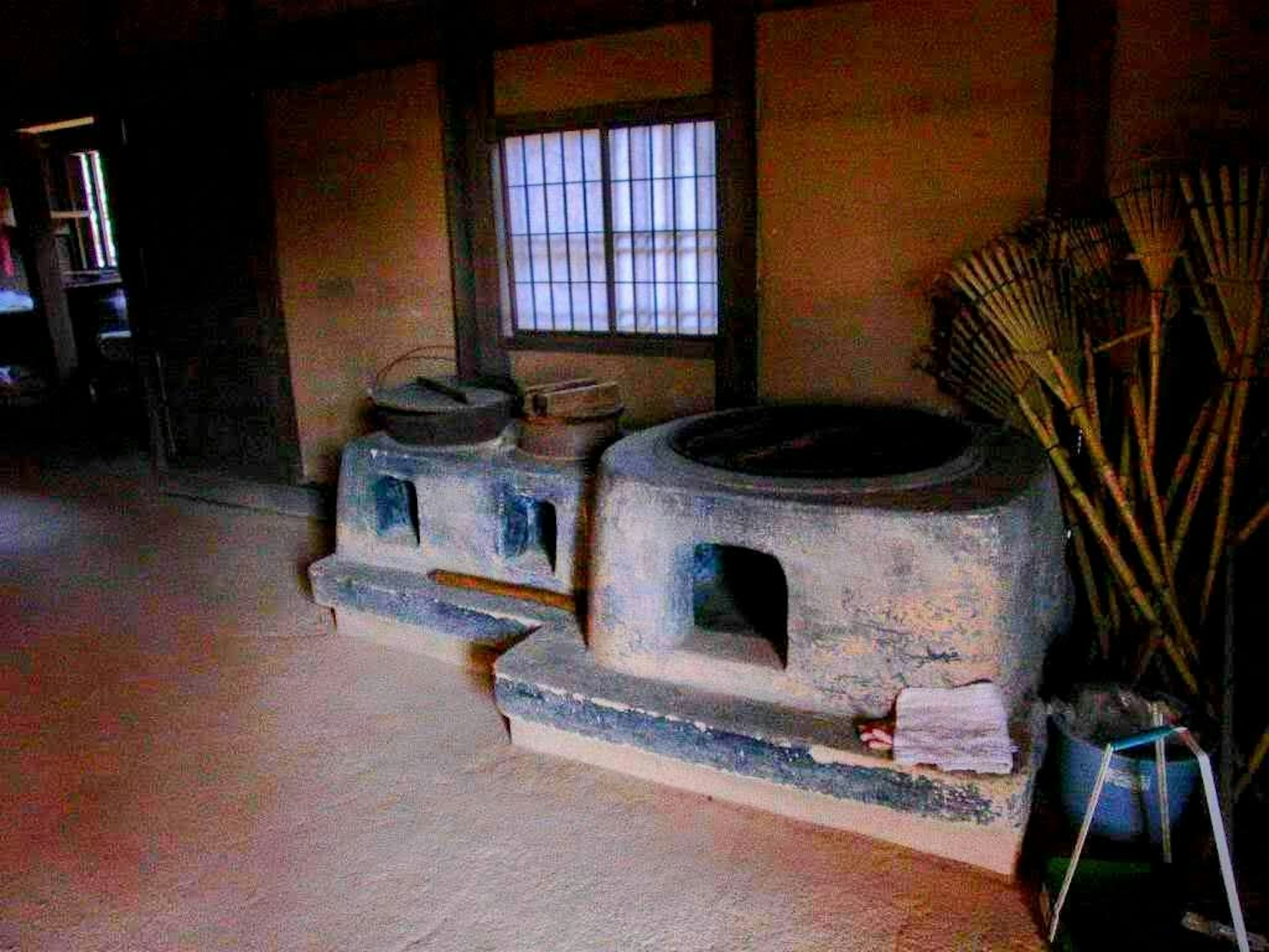 Interno di una casa tradizionale giapponese con un focolare in argilla e strumenti in bambù