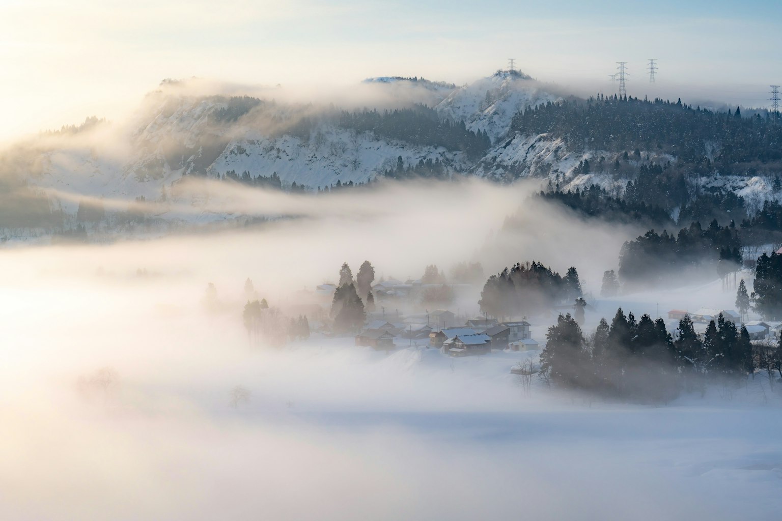 Beautiful landscape of snow-covered mountains and a village enveloped in fog