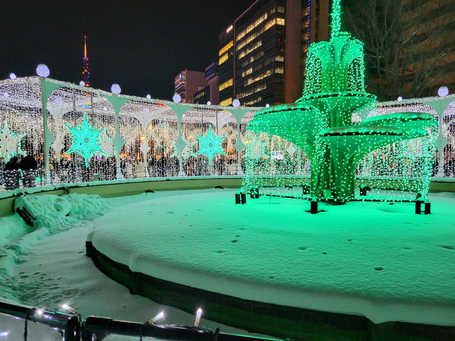 夜晚雪覆廣場中的綠燈裝飾噴泉