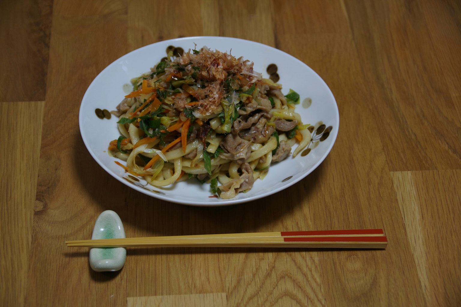 Món udon được phục vụ trên đĩa trắng với rau và topping nhiều màu sắc