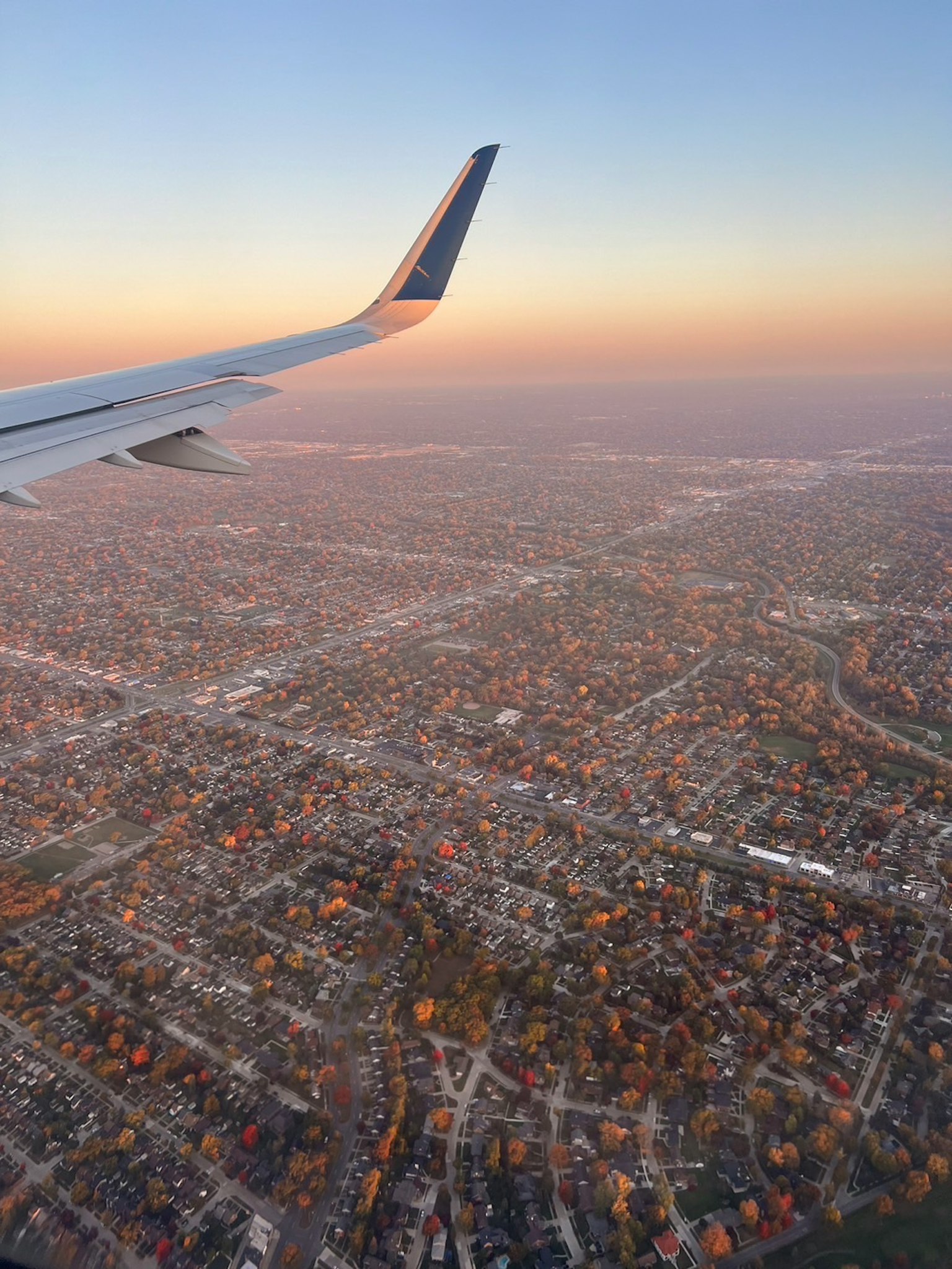 Airplane wing with sunset over a cityscape